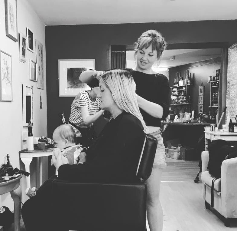 A lady in a salon cutting the blonde hair of a woman.